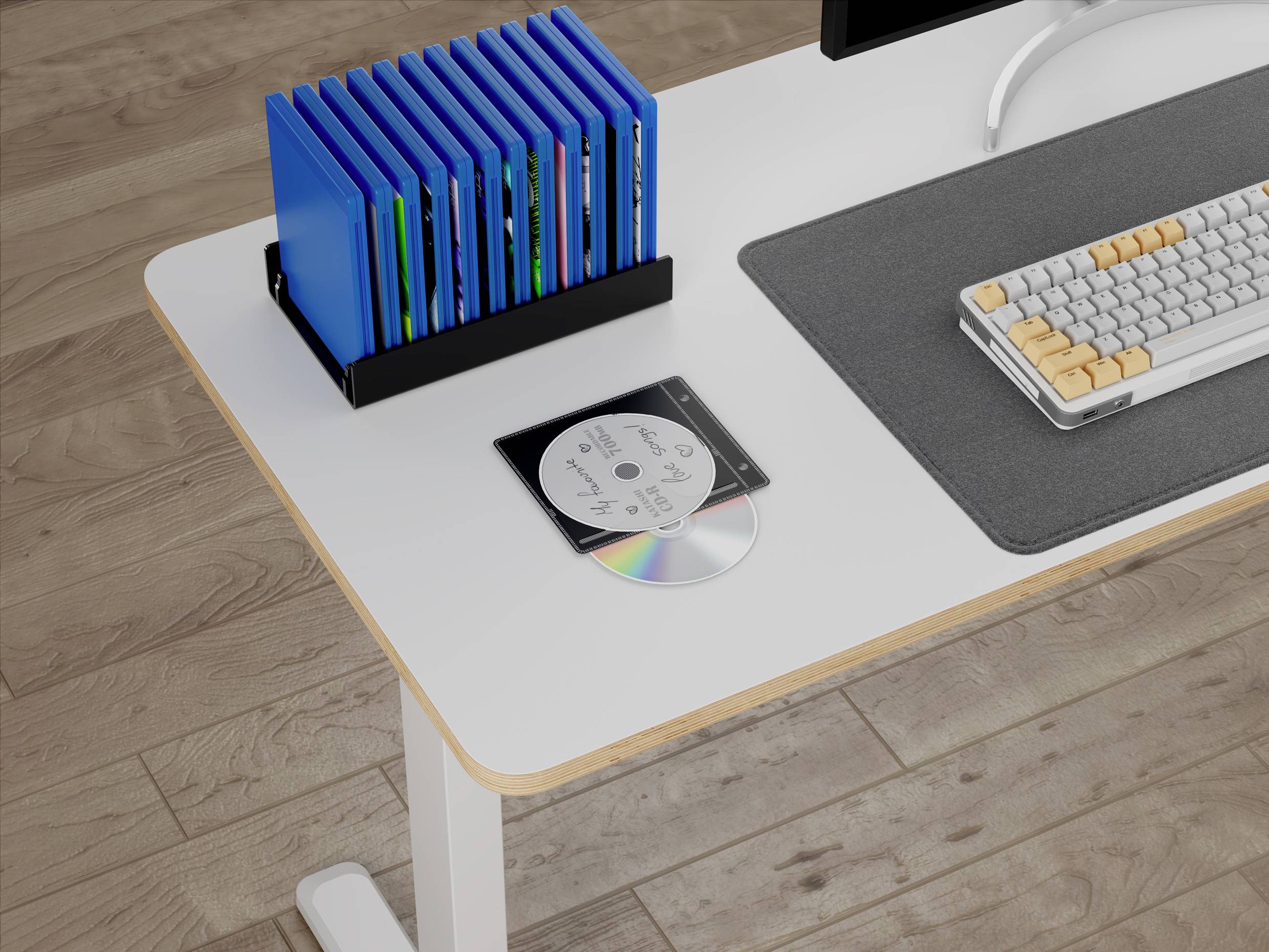 Ein weißer Schreibtisch mit einer Tastatur, einer dunkelgrauen Matte, einer CD mit Hülle und einem Ständer mit blauen Ordnern, alles auf einem Holzboden.