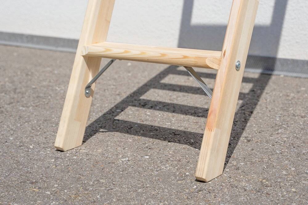 Ein Holztritt mit Schatten auf Betonboden bei Tageslicht.