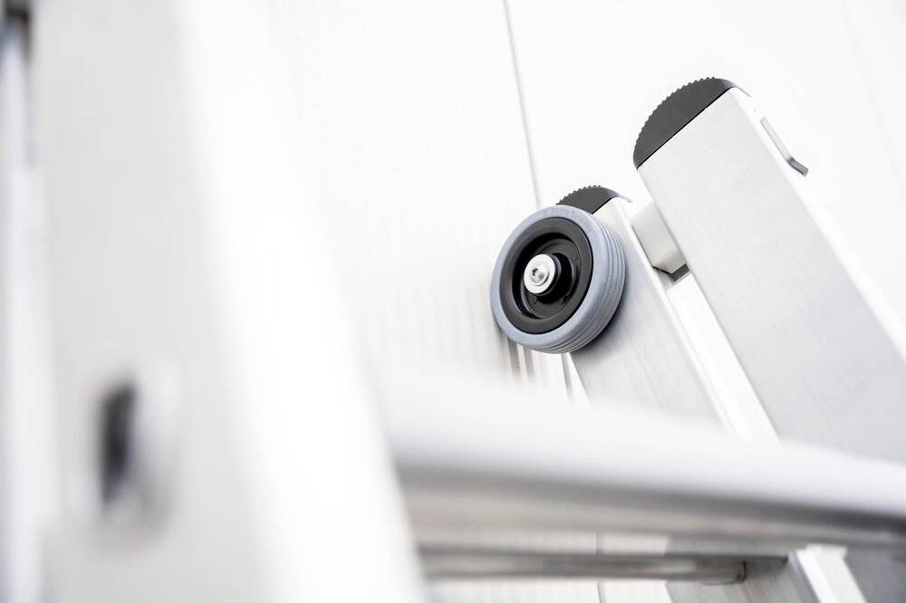 Eine Nahaufnahme einer Leiter mit einem Rad auf einer der Stufen, aus einem Winkel aufgenommen, der die Länge der Leiter betont.