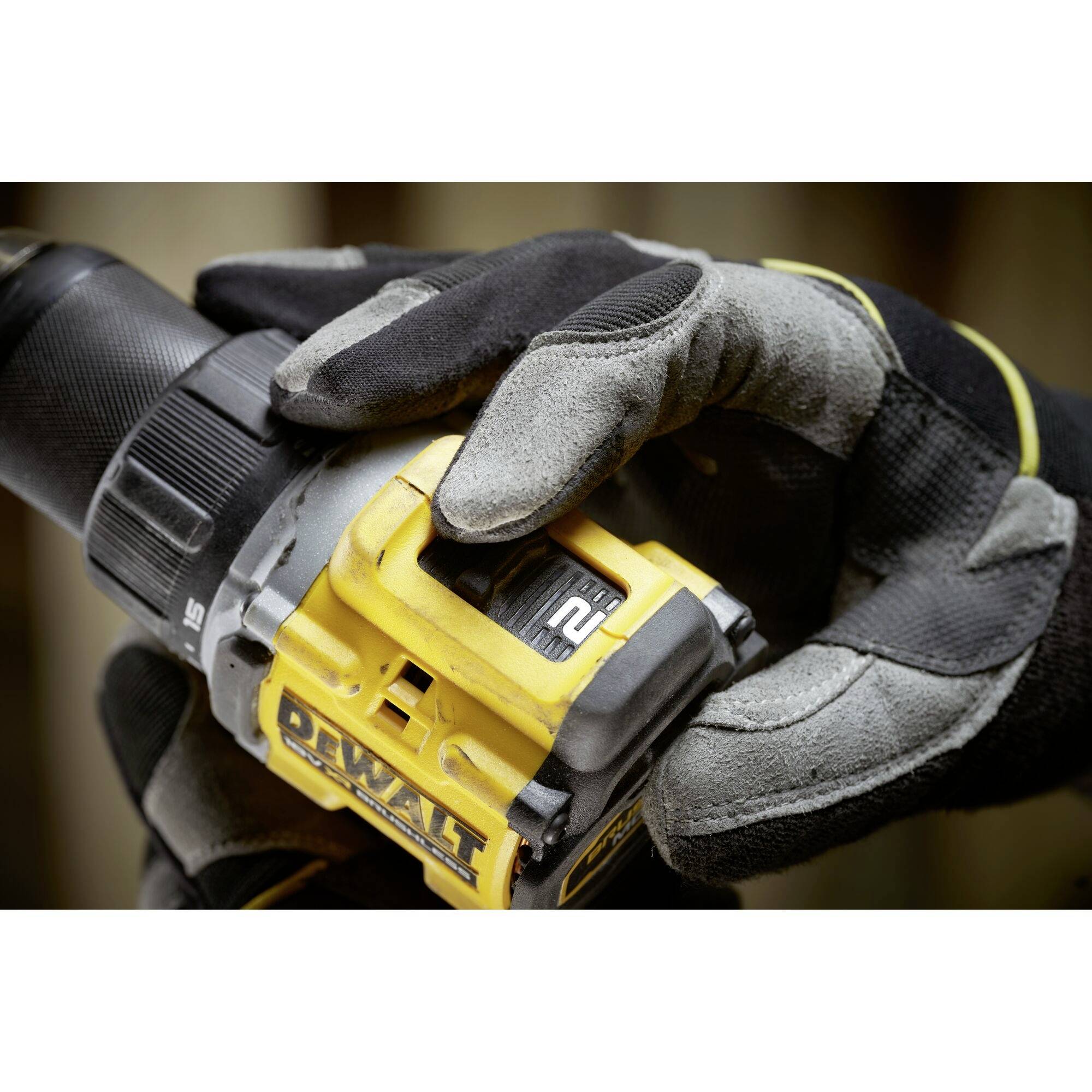 Eine Hand mit Handschuhen hält einen gelben Akkubohrer.