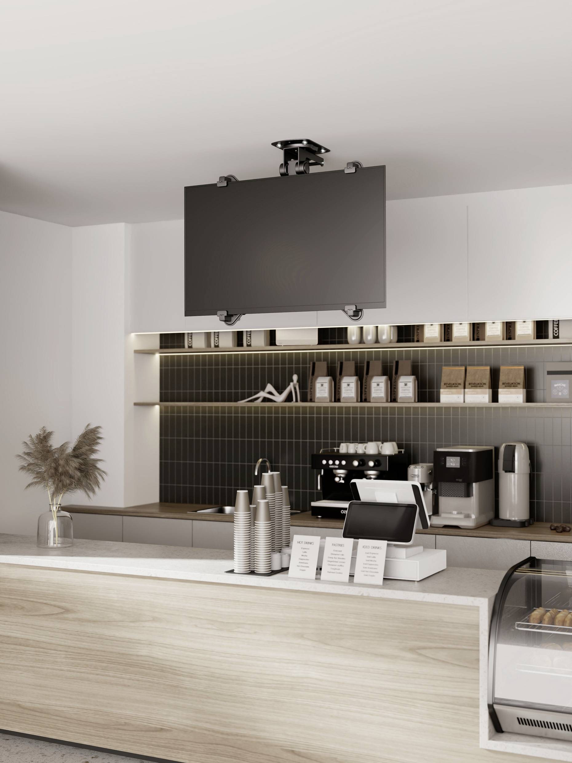 Ein stilvolles Café mit moderner Einrichtung, Kaffeemaschine, und Kaffeezubehör auf der Theke. Ein Bildschirm hängt an der Decke.