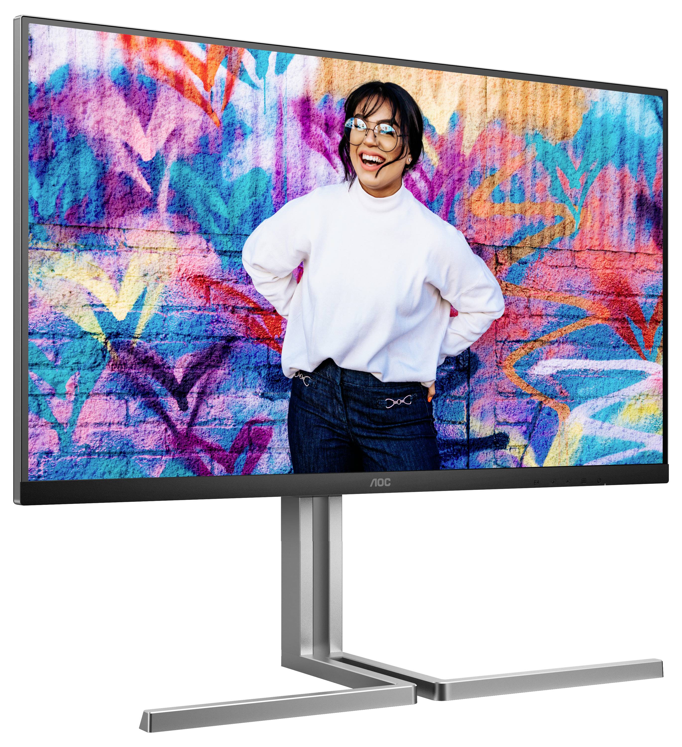 Ein fröhlicher Mensch mit Brille und weißem Pullover steht vor einer bunten, graffiti-bemalten Wand.