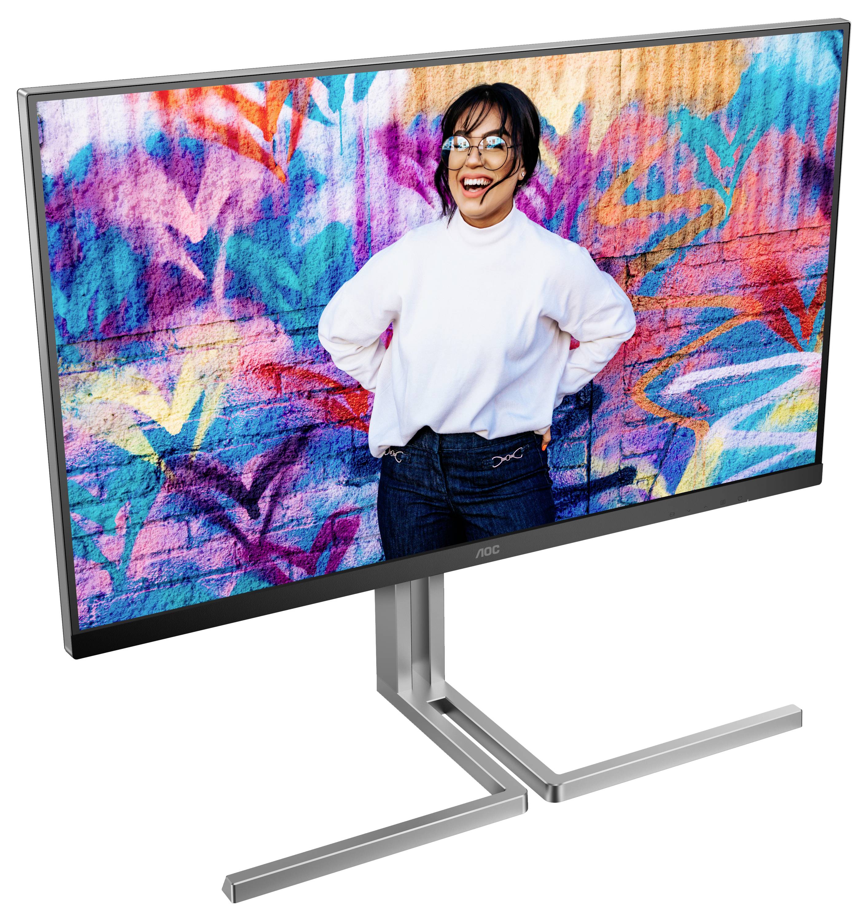 Frau steht lächelnd vor einer bunt gesprayten Wand, die lebhafte Farben und Muster zeigt. Sie trägt einen weißen Pullover.