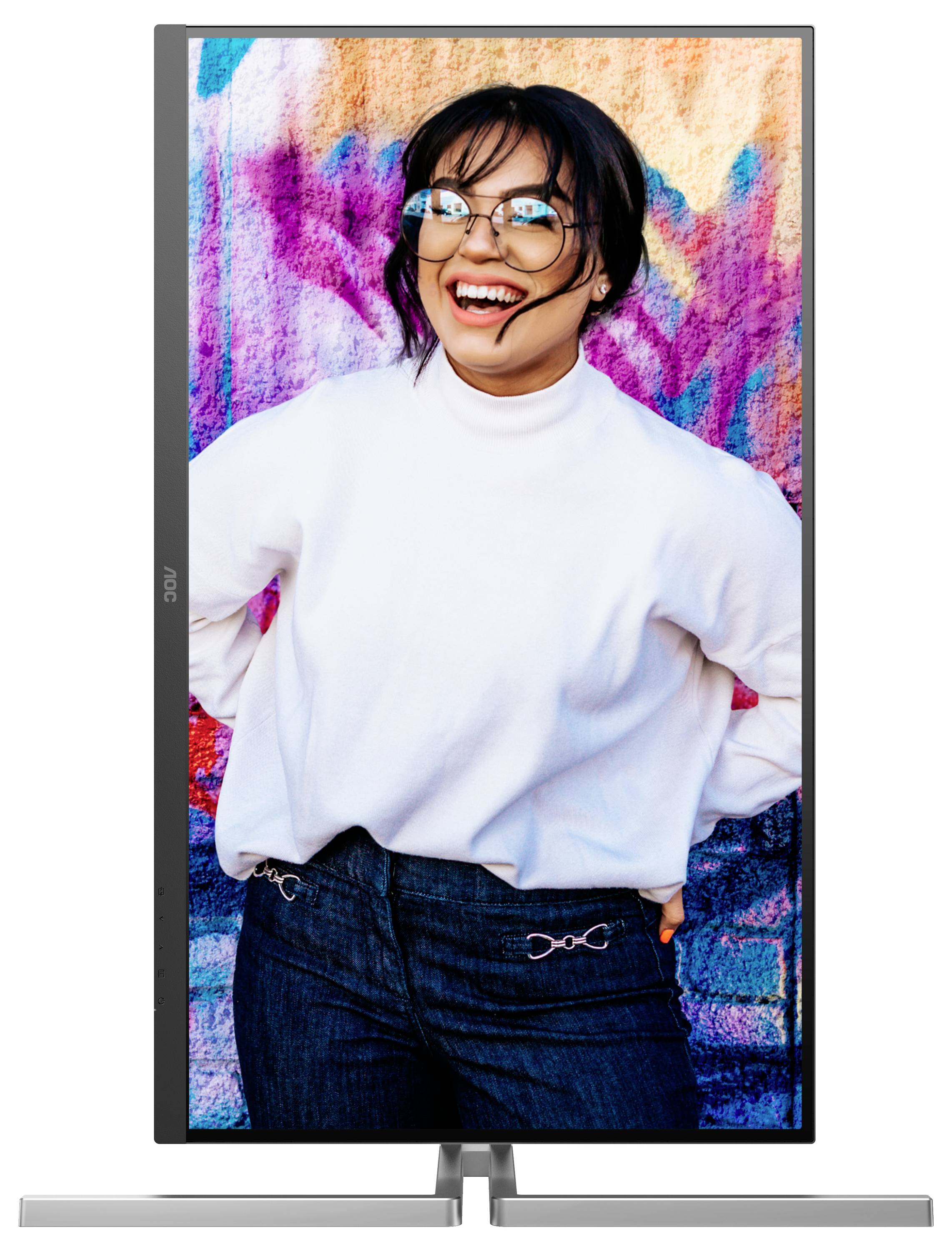 Frau mit Brille und weißem Pullover lacht vor einer farbenfrohen Wand.