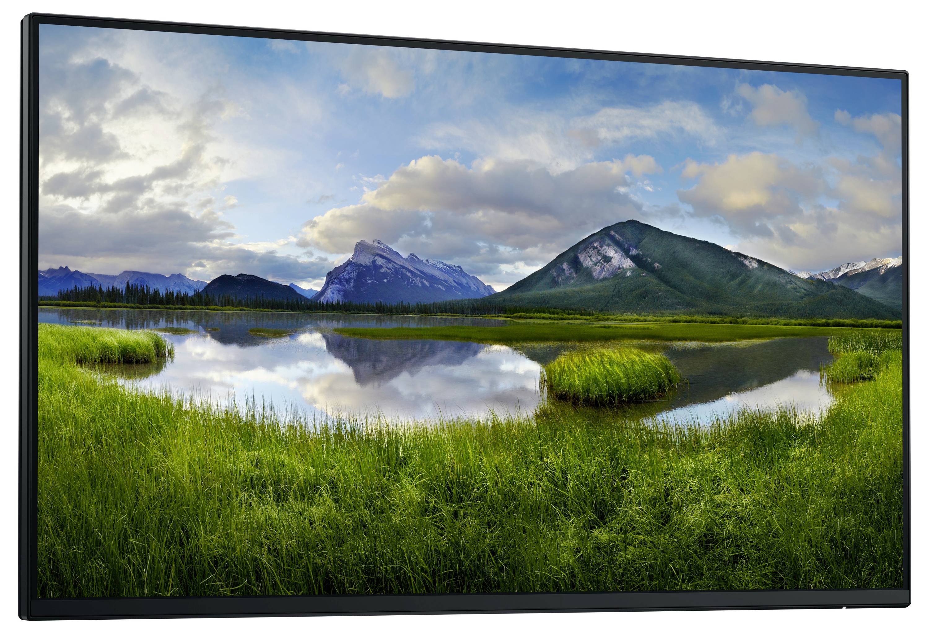 Eine ruhige Landschaft mit einem See, der von grünen Wiesen umgeben ist. Berge und ein bewölkter Himmel spiegeln sich im Wasser wider.