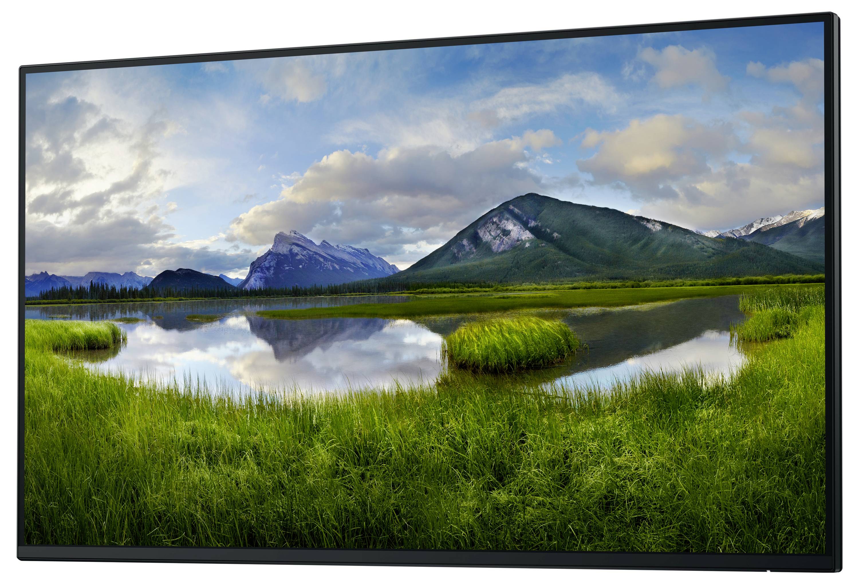 Landschaftsfoto von einem ruhigen See mit grünen Ufern, umgeben von Bergen unter einem bewölkten Himmel.