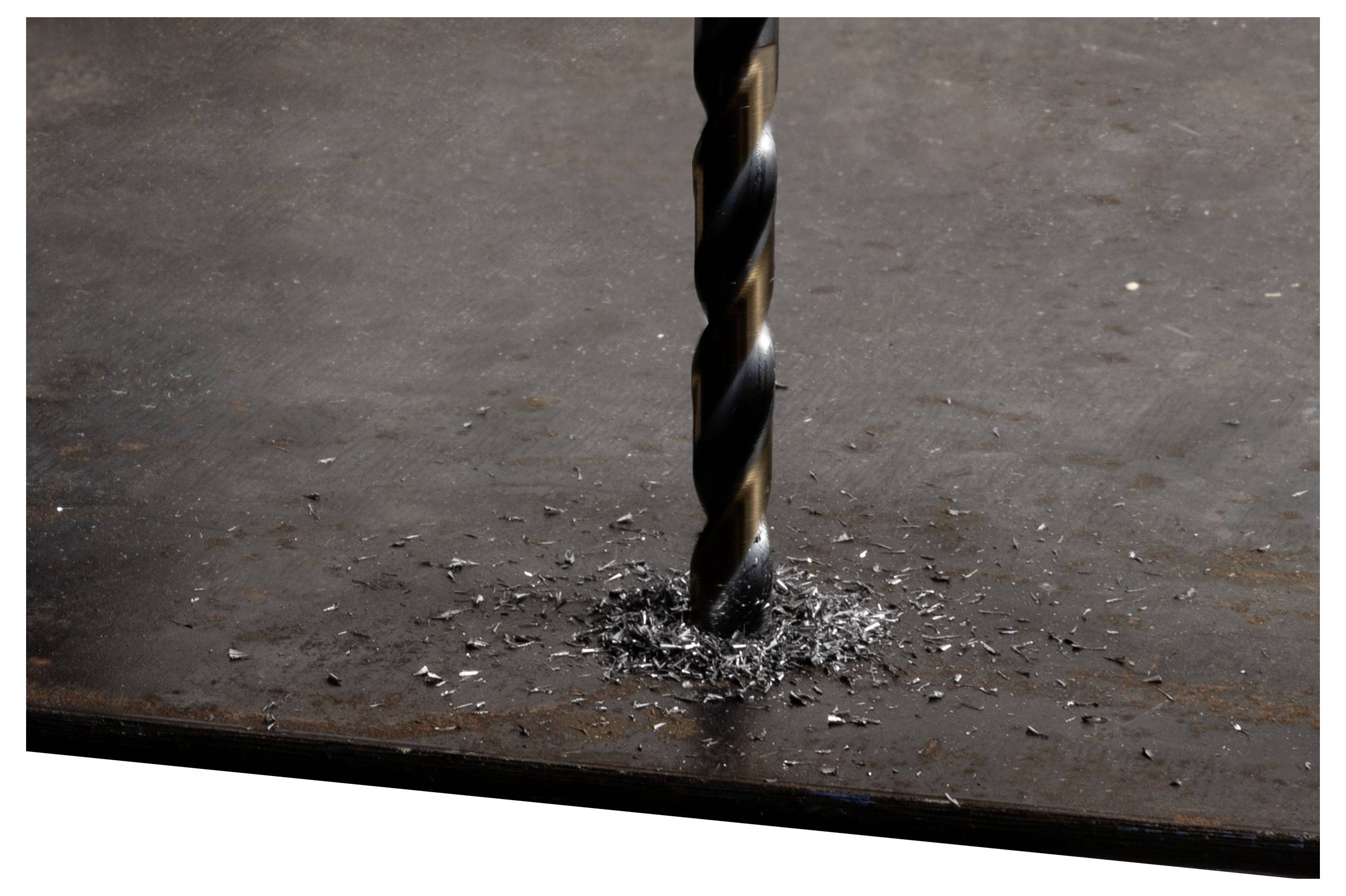 Ein Bohrer durchdringt eine flache Stahloberfläche und erzeugt kleine Metallspäne um das Loch herum.