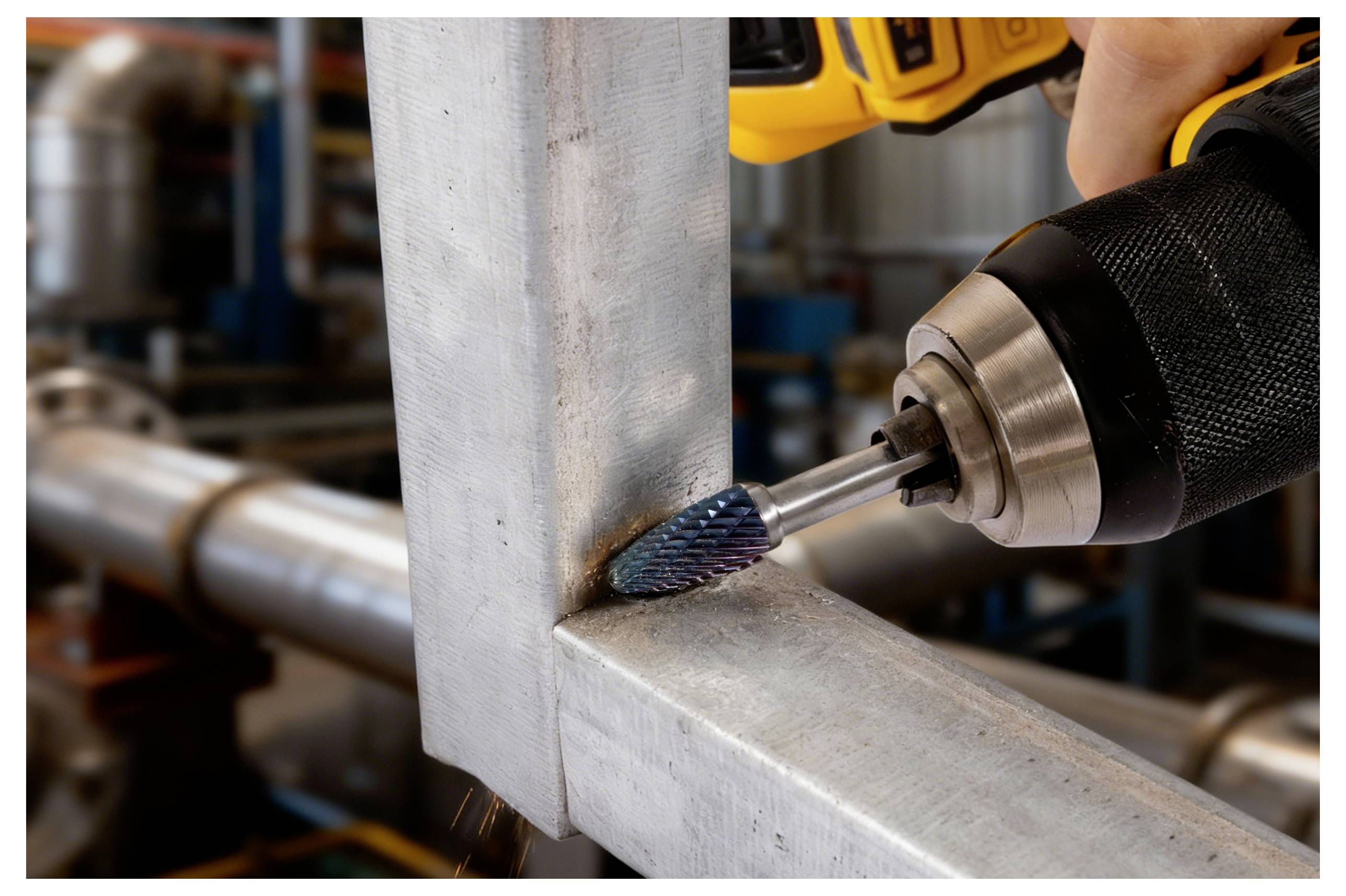 Eine Powertools mit einem blauen zylindrischen Bit schleift einen Metallrahmen in einem industriellen Umfeld und betont den Prozess des Metallfinishings.