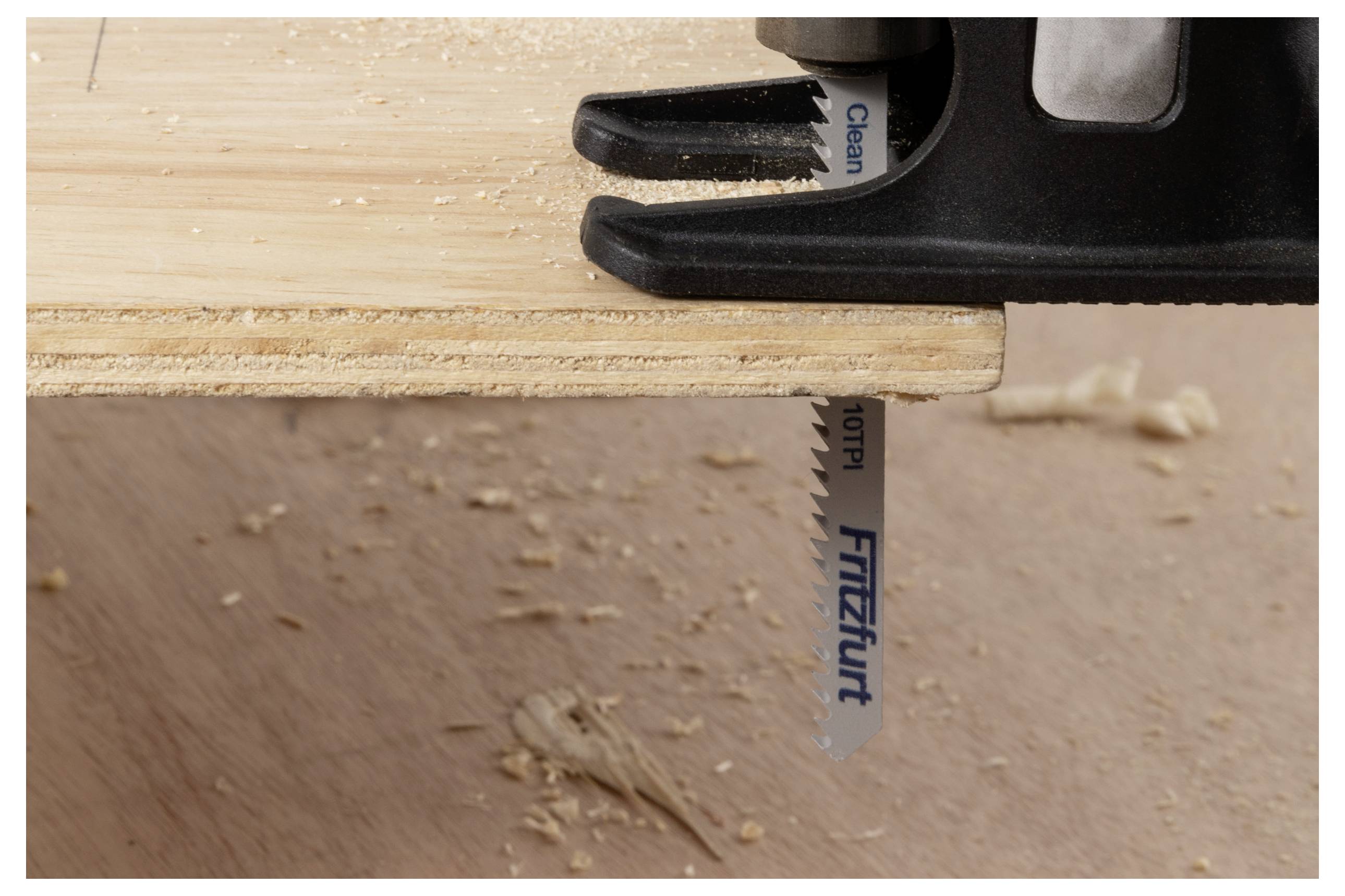 Eine Stichsäge, die durch eine Sperrholzplatte schneidet, mit Holzspänen, die unterhalb des Schnitts verstreut sind.