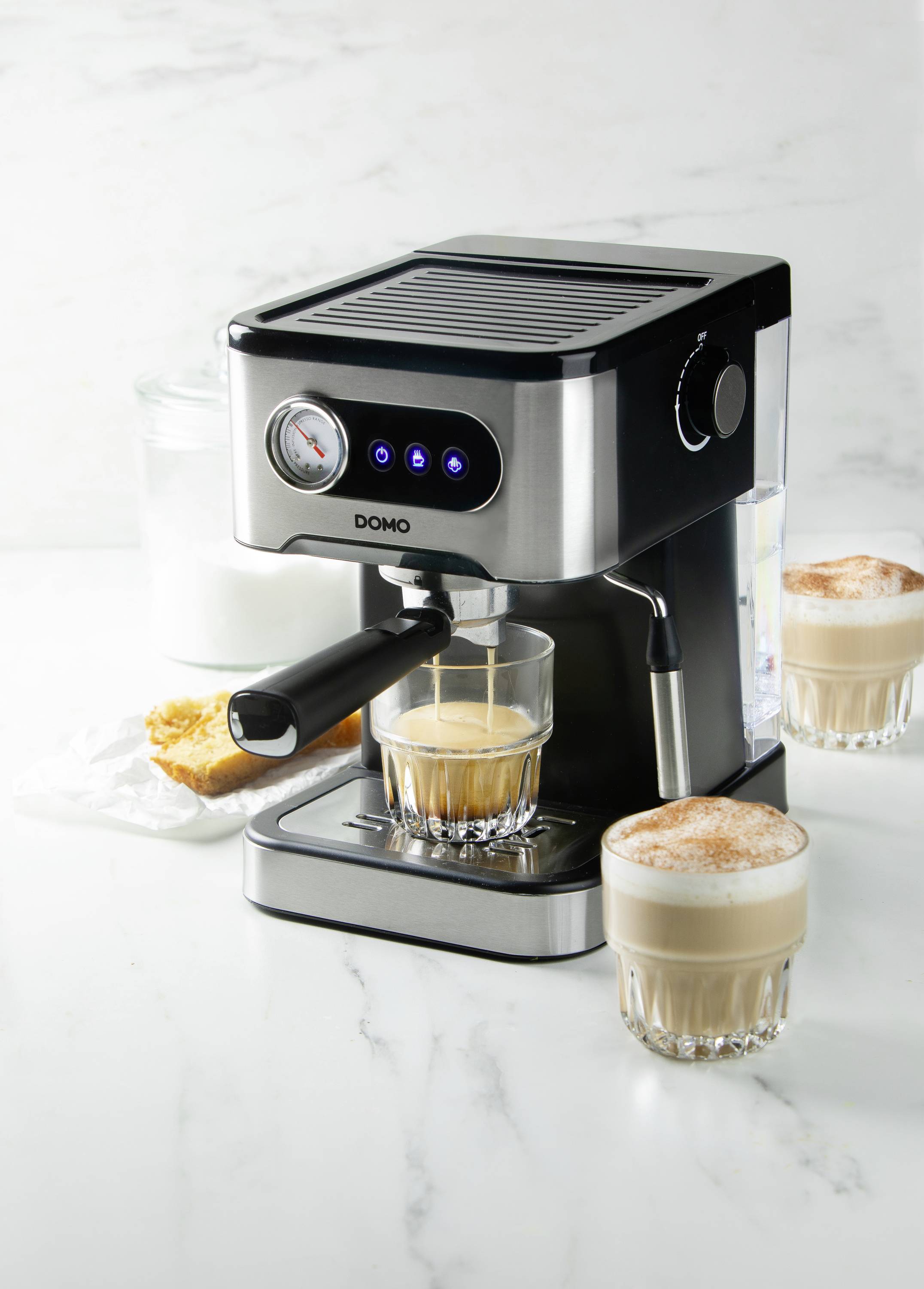 Espressomaschine mit zwei Gläsern Cappuccino auf Marmoroberfläche im modernen Küchenambiente.
