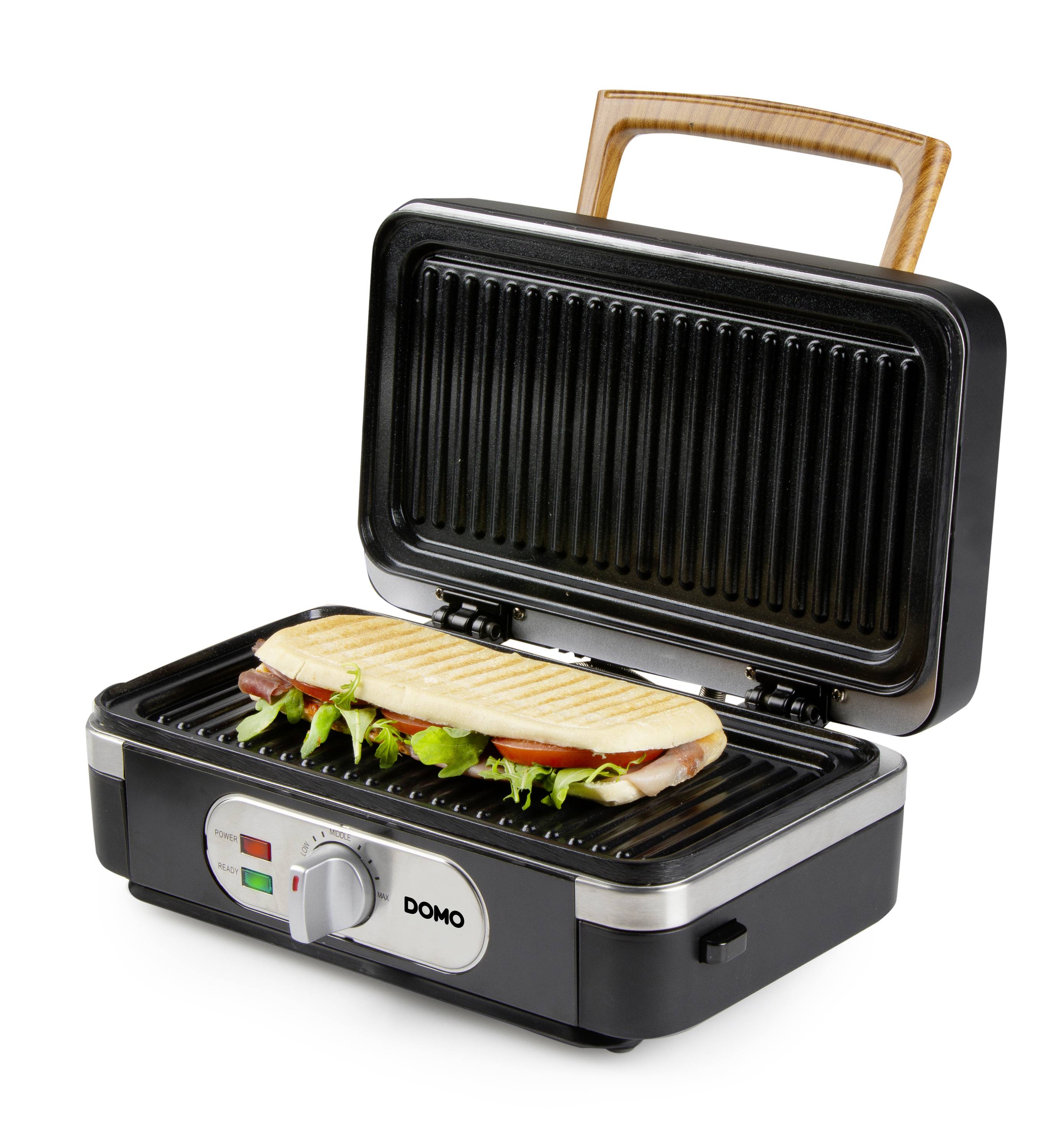 Ein elektrischer Grill mit einem Panini-Sandwich darin, der Deckel ist offen. Der Grill hat ein hölzernes Griffdesign.