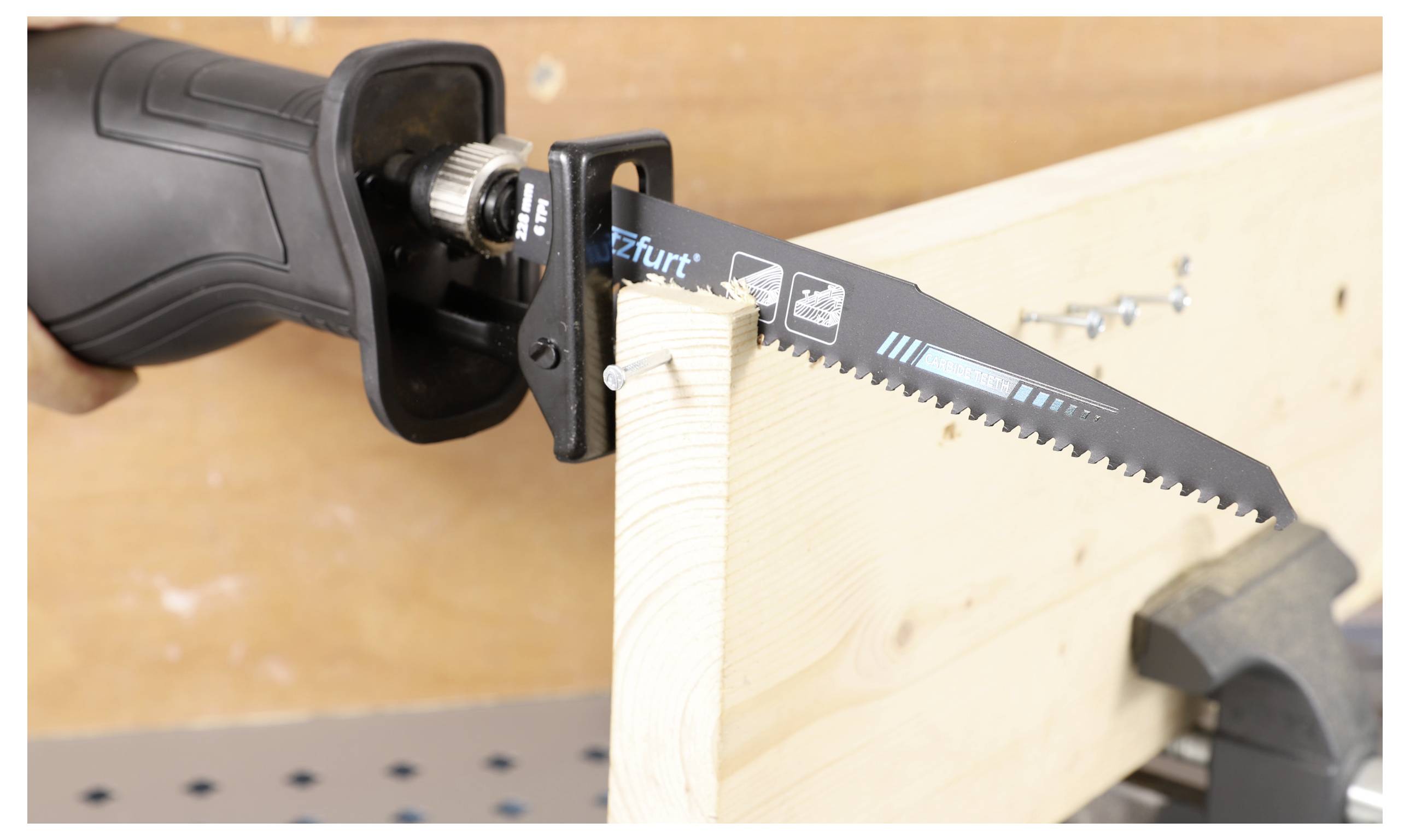 Ein Elektroschnellhacker, der durch ein Holzbrett mit mehreren teilweise durchschnittenen Schrauben schneidet, eingespannt in einem Schraubstock auf einer Werkbank.
