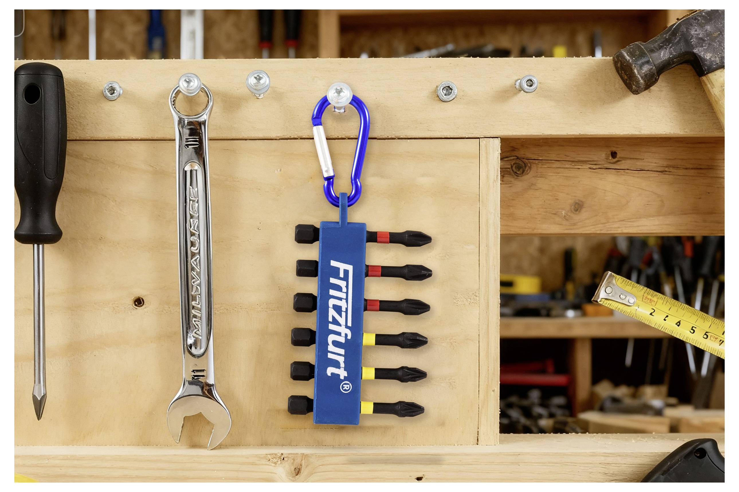 Eine Werkbank mit einem montierten Werkzeugbrett hält einen Schraubendreher, einen Schraubenschlüssel und einen blauen Karabiner mit mehreren Schraubendreher-Bits, beschriftet mit 'Fritzfurt'.
