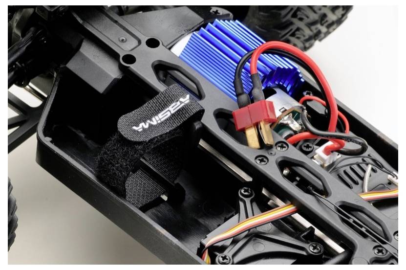 Eine detaillierte Ansicht eines Fernsteuerauto-Chassis, das die elektronischen Komponenten und Verkabelung zeigt, einschließlich eines blauen Kühlkörpers und Stromkabel.