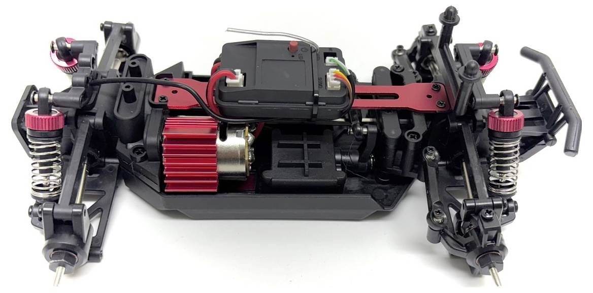 Nahaufnahme eines ferngesteuerten Autochassis. Sichtbar sind die Aufhängung, Stoßdämpfer und der Elektromotor.