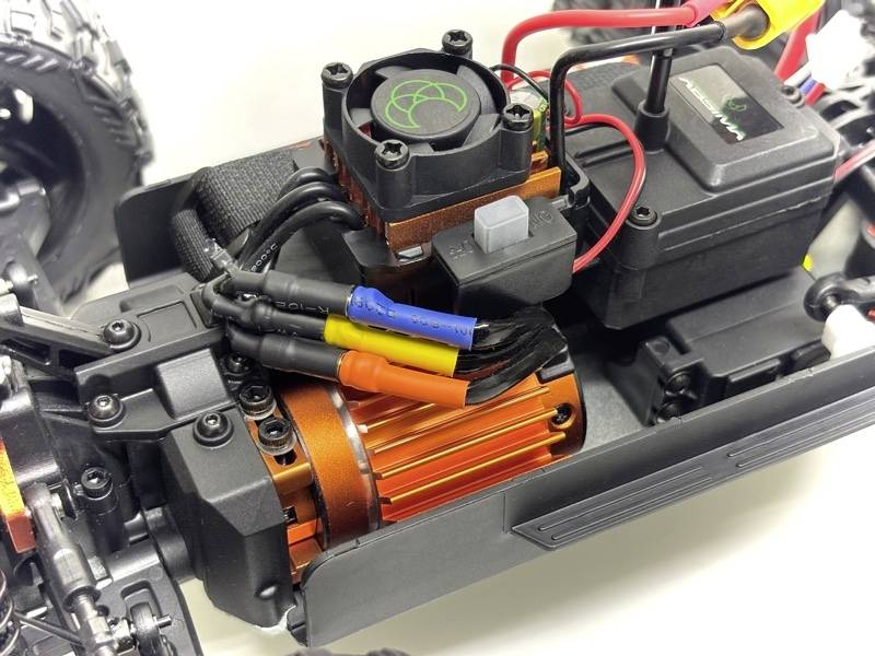 Nahaufnahme eines ferngesteuerten Autos, zeigt den Motor mit farblich gekennzeichneten Kabeln und einem Lüfter zur Kühlung.