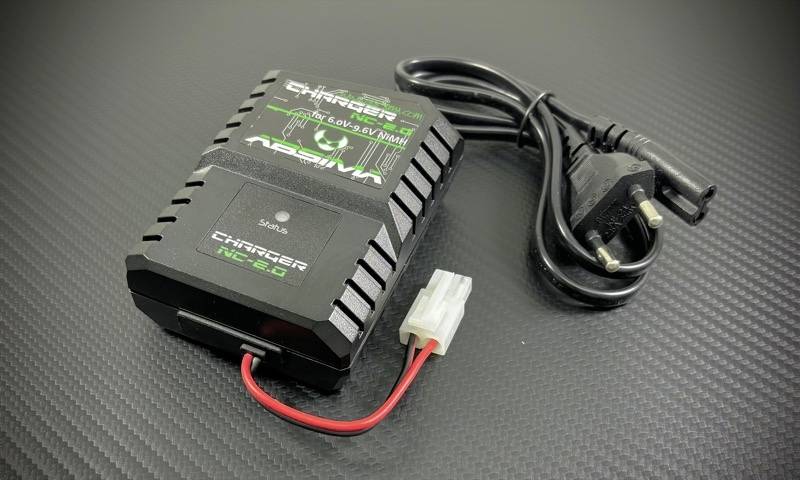 Ein kleiner, schwarzer Akku-Ladegerät mit Stecker und Kabel liegt auf einer dunklen, strukturierten Oberfläche.