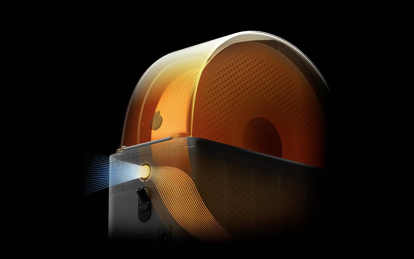 Orange förmiges Objekt in dunkel beleuchtetem Raum, das von rechts strahlt. Moderne Technik, möglicherweise ein Ventilator oder Luftreiniger.