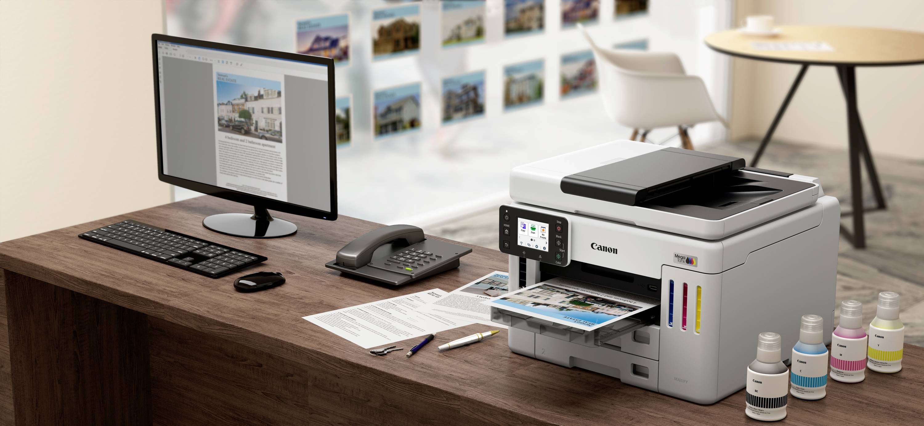 Ein Drucker auf einem Bürotisch druckt ein farbiges Dokument. Daneben stehen ein Monitor, eine Tastatur, ein Telefon und Tintenflaschen.