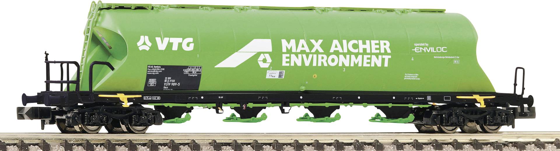 Grüner Güterwaggon mit weißem Logo 'MAX AICHER ENVIRONMENT'. Zugwaggon auf Gleisen, seitliche Ansicht.