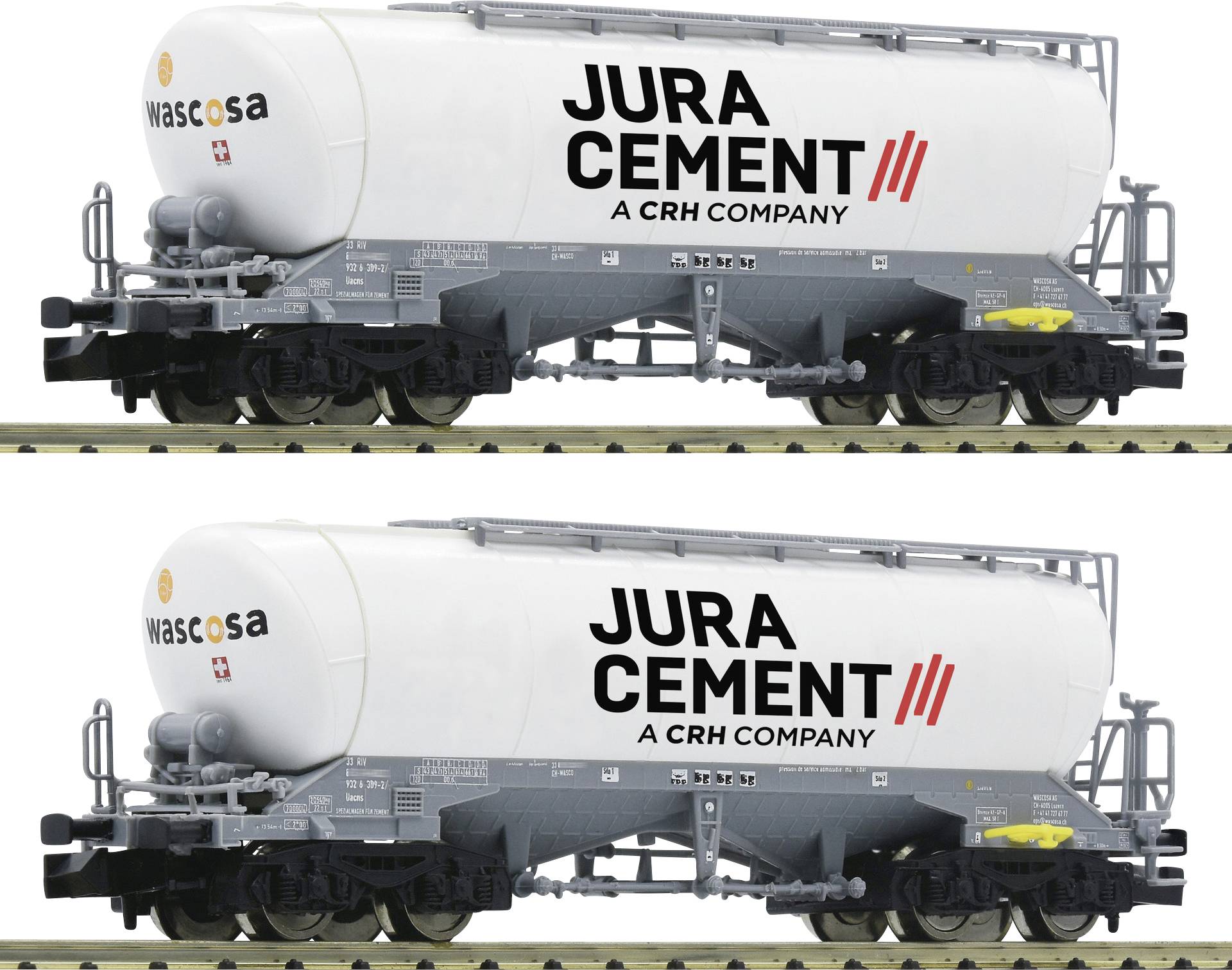 Zwei Zementwaggons mit den Aufschriften 'Jura Cement - A CRH Company' und 'Wascosa' auf den Seiten, auf einem Gleis stehend.