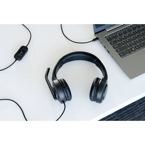 Kopfhörer mit Mikrofon auf einem weißen Tisch neben einem Laptop. Veranschaulicht Büro- oder Homeoffice-Umgebung für Kommunikation.