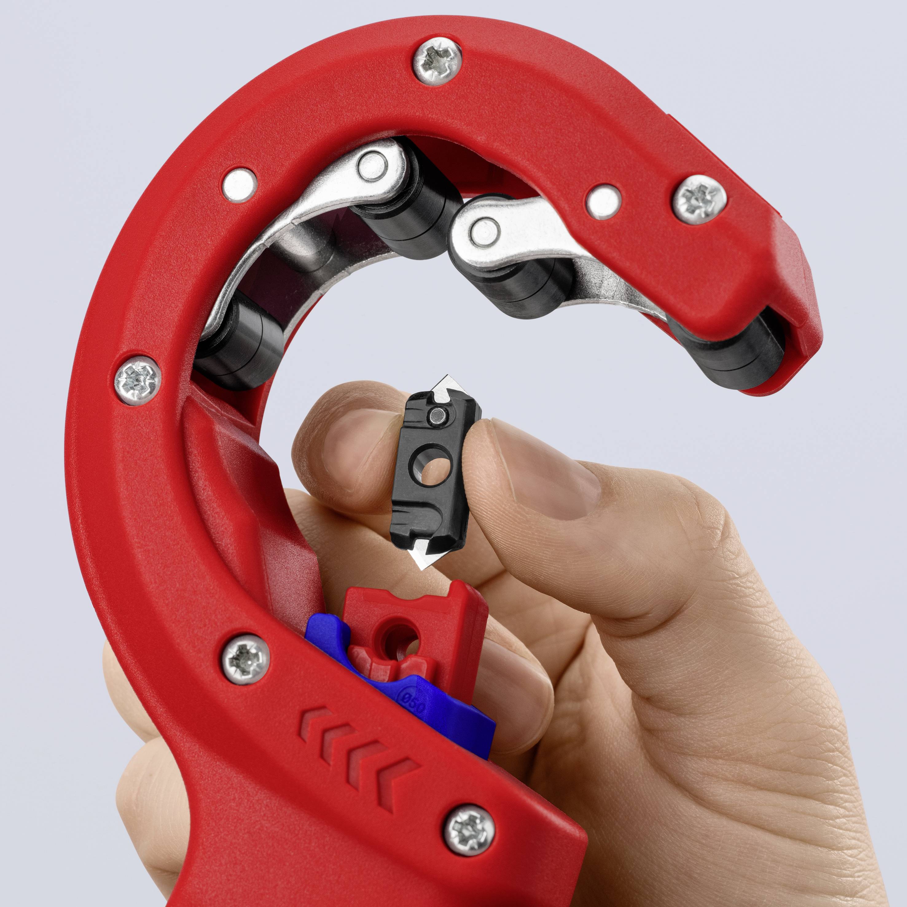 Rote Rohrschneider-Zange wird von einer Hand gehalten, zeigt scharfe Klinge und Einstellrad. Werkzeug wird für präzises Schneiden von Rohren genutzt.