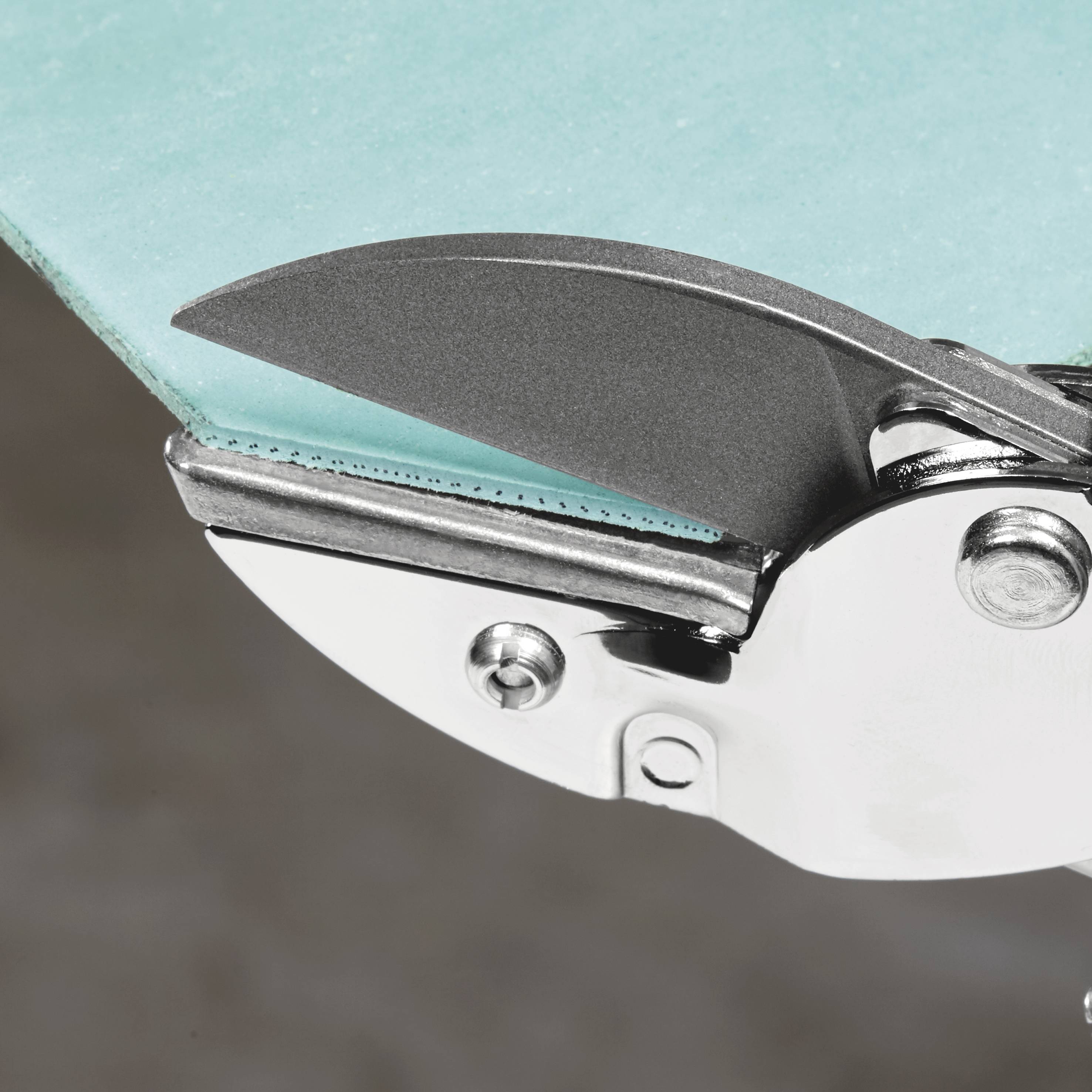 Nahaufnahme der scharfen, metallischen Klinge eines Cuttermessers, die gegen einen türkisfarbenen Hintergrund zeigt.