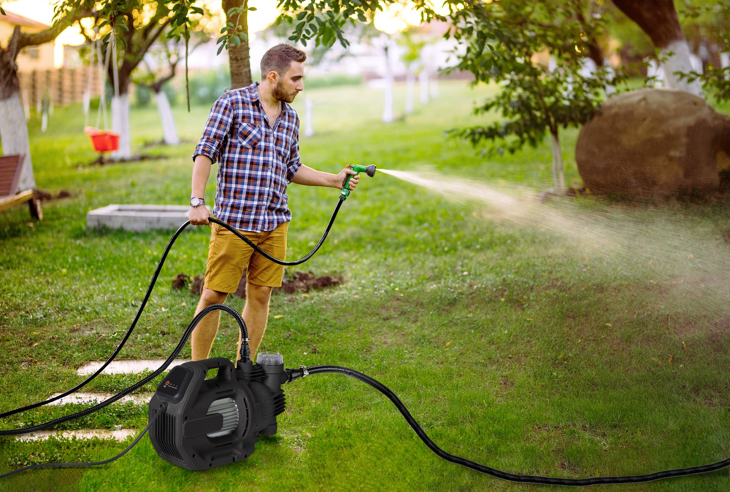 Ein Mann benutzt eine Wasserpumpe, um einen grünen Rasen in einem Hinterhof zu bewässern, der von Bäumen umgeben ist und dabei einen Moment der Gartenarbeit im Freien einfängt.