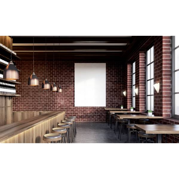 Ein modernes Café mit roten Backsteinwänden, hölzerner Theke, Hockern und Tischen. Die warmen Lampen erzeugen eine gemütliche Atmosphäre.