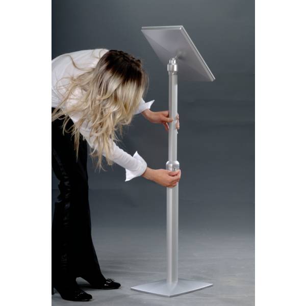 Eine Person justiert die Höhe eines silbernen Informationsständers mit einem Schild darauf.