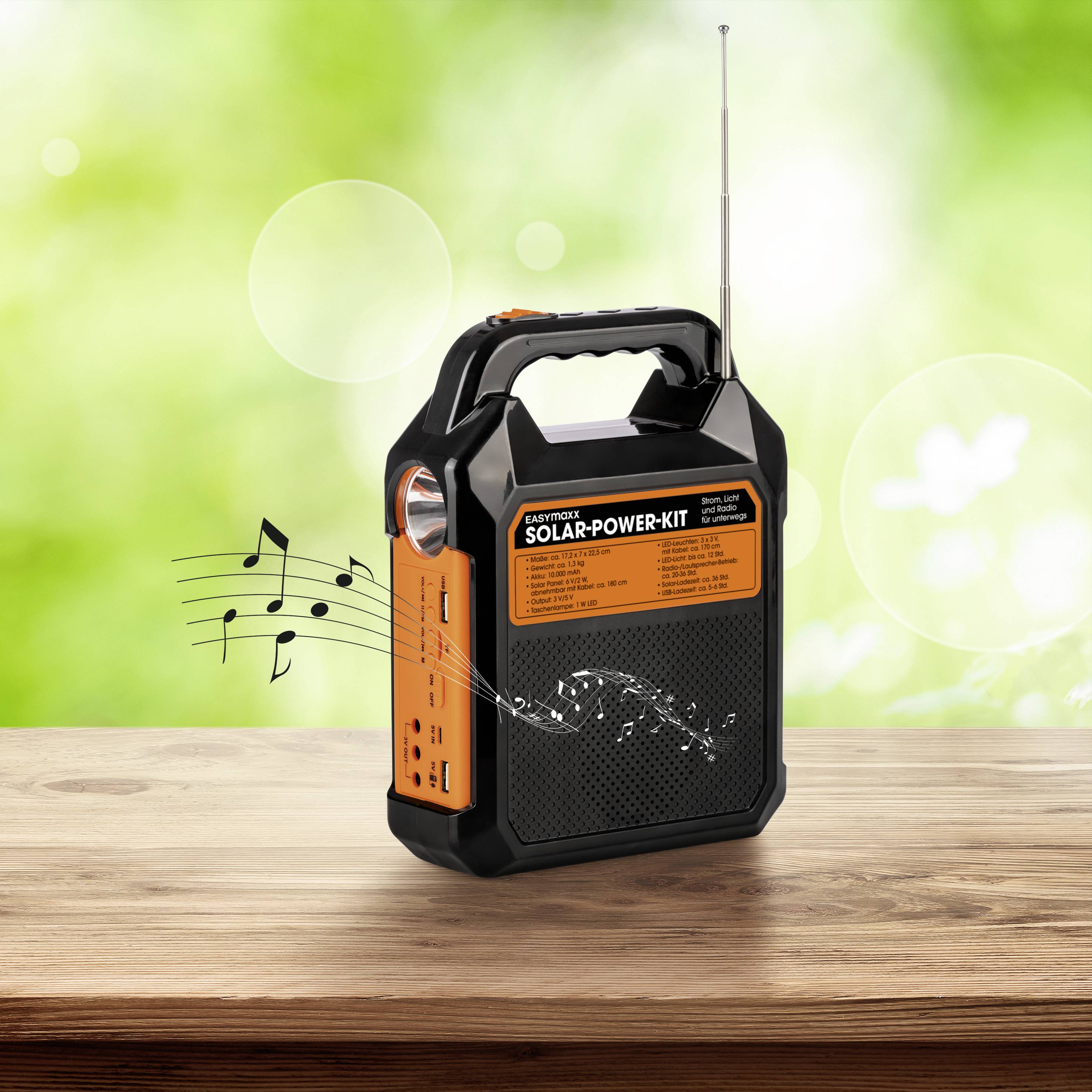 Ein tragbares, orange-schwarzes Solar-Radiokompaktgerät auf einem Holztisch. Musiknoten zeigen, dass es Musik abspielt. Hintergrund grün verschwommen.