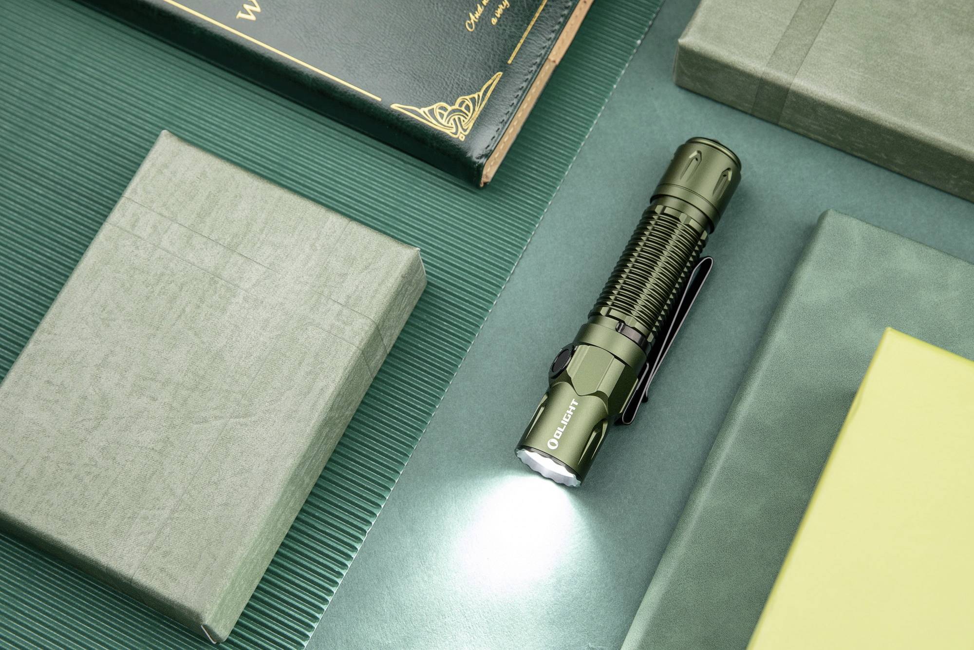 Eine grüne Taschenlampe strahlt Licht auf eine grüne Oberfläche. Umgeben von Büchern, ist sie zentral positioniert und beleuchtet.