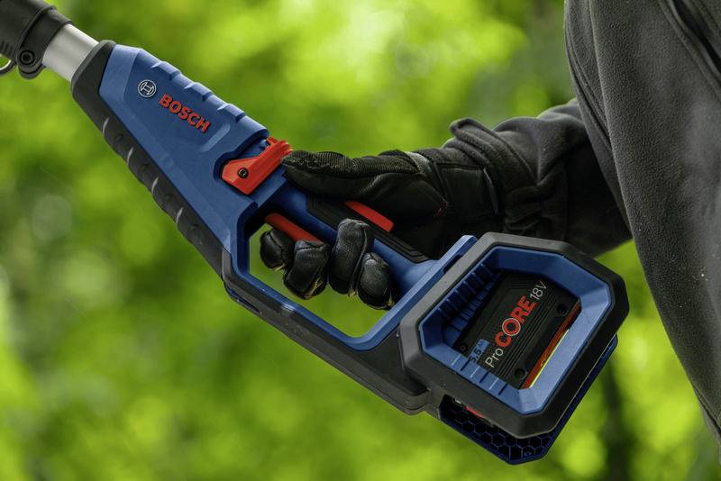 Akkugerät von Bosch, gehalten von einer Person in schwarzem Handschuh. Das Gerät ist blau mit roten Akzenten, im Freien bei grünem Hintergrund.