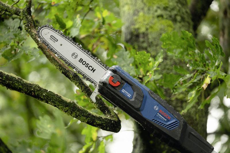 Eine Elektro-Kettensäge schneidet einen Ast von einem Baum. Die Säge ist blau-schwarz mit dem Schriftzug 'Bosch'.