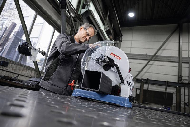 Ein Mann arbeitet in einer Werkstatt an einer Bosch-Kreissäge, umgeben von industrieller Ausrüstung.