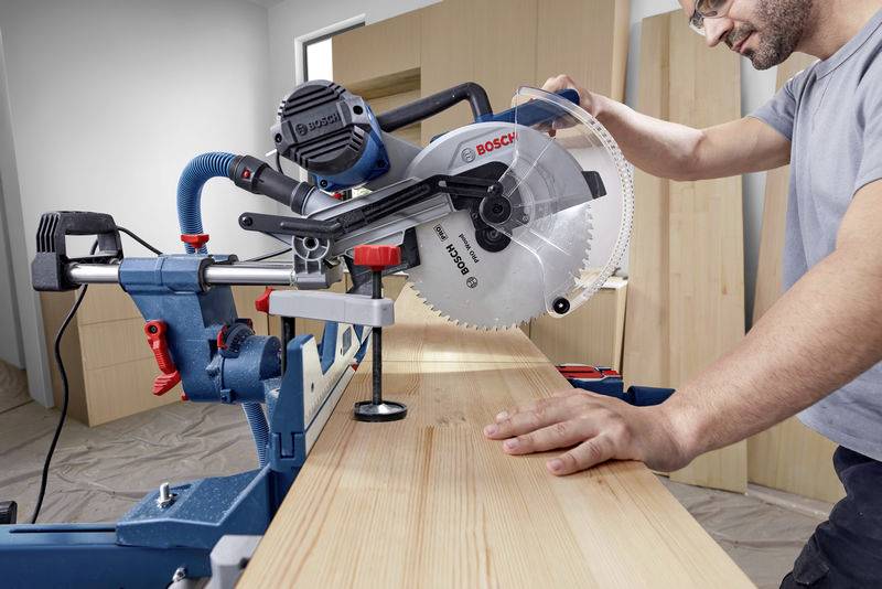 Eine Person schneidet ein Holzbrett mit einer Tischkreissäge. Die Werkstatt ist gut beleuchtet. Der Fokus liegt auf präzisem Sägen.