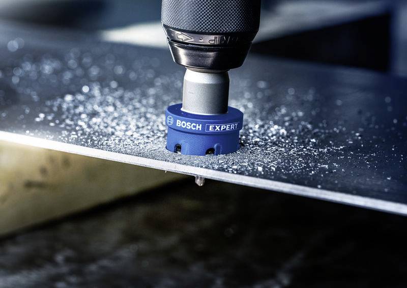 Ein Bohrkopf von Bosch bohrt ein präzises Loch in ein Metallblech, während Späne um die Bohrstelle herum verstreut sind.
