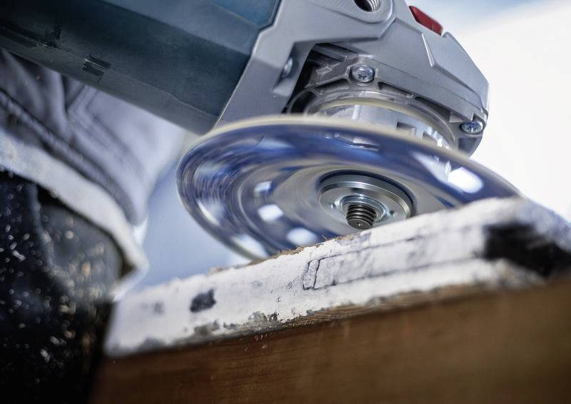 Eine Nahaufnahme eines Winkelschleifers, der ein Stück Holz bearbeitet. Funken fliegen, was die Bewegung und Tätigkeit zeigt.