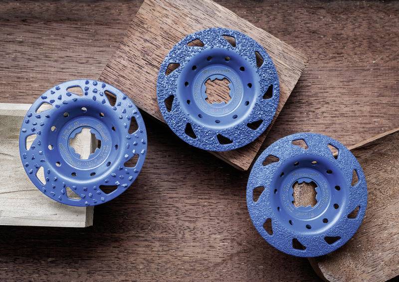 Drei blaue Schleifscheiben mit unterschiedlichen Texturen liegen auf Holzbrettern. Sie sind kreisförmig mit unregelmäßigen Mustern.