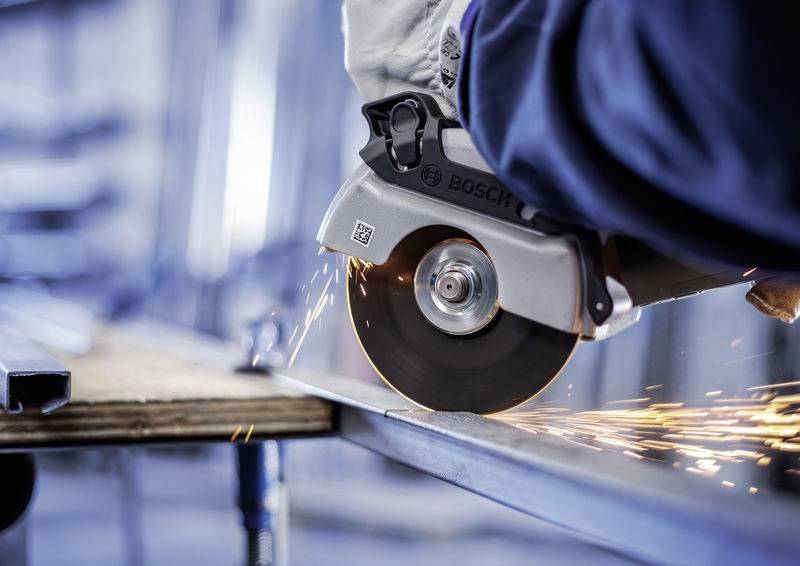 Person schneidet mit Winkelschleifer Metall, Funken sprühen. Arbeitsschutzhandschuhe werden getragen. Industrielle Umgebung.