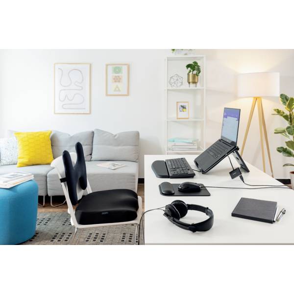 Ein modernes, ergonomisches Homeoffice. Links ein graues Sofa, rechts ein Schreibtisch mit Laptop, ergonomischer Maus und Tastatur.