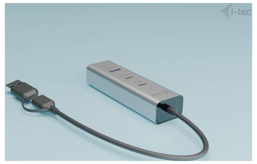 Ein silberner USB-Hub mit vier Anschlüssen, verbunden mit einem USB-Kabel, liegt auf einer hellblauen Oberfläche.