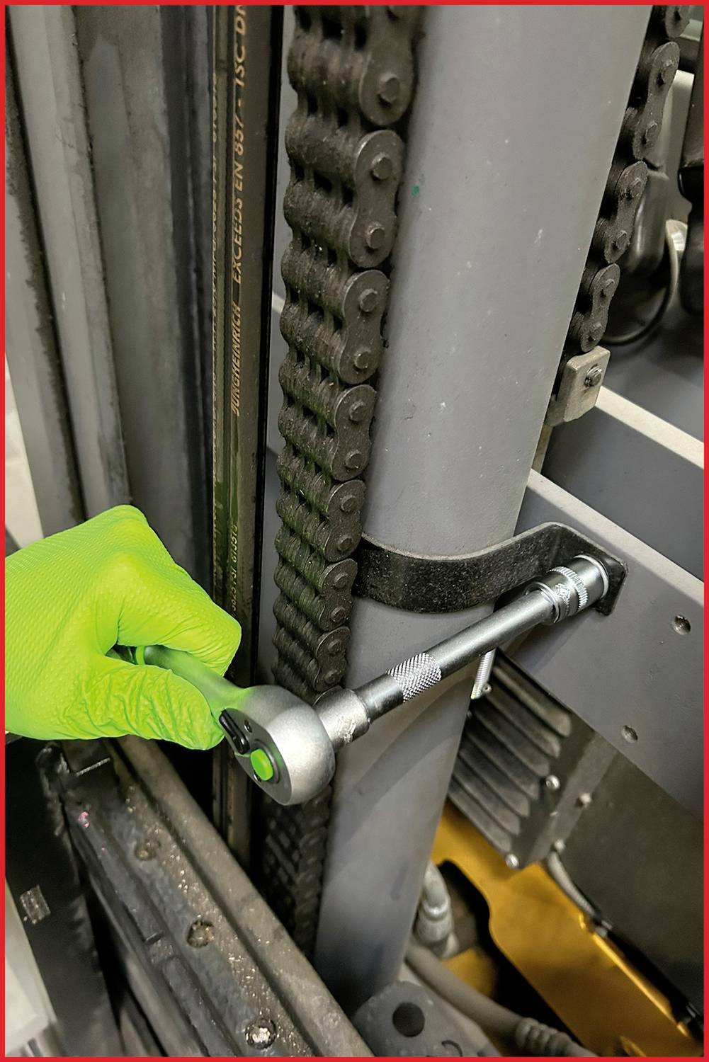 Ein geöffneter Werkzeugkasten mit Schraubenschlüsseln und Steckschlüsseln liegt vor einem Gabelstapler in einer Werkstatt.