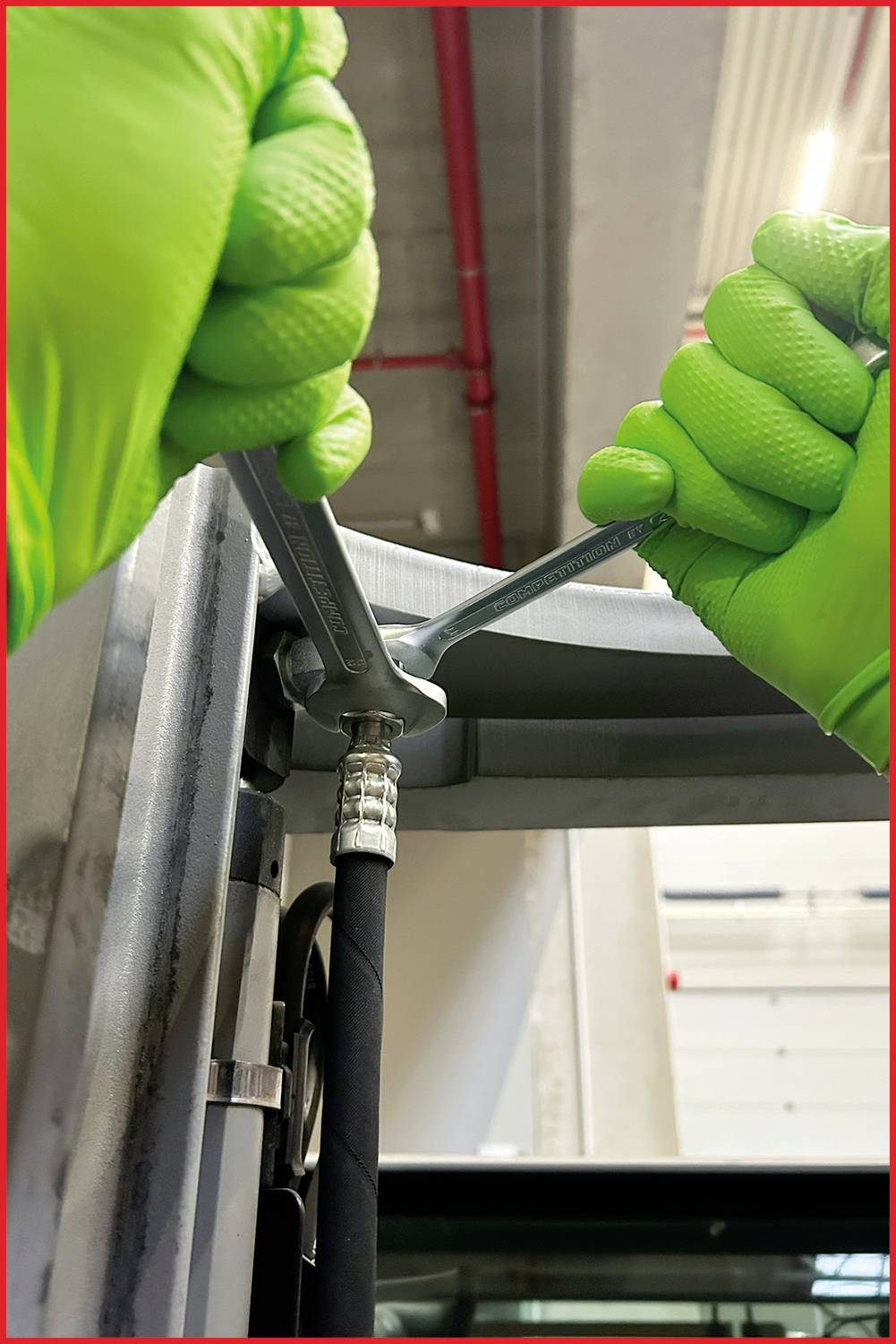 Person in grünen Handschuhen repariert eine Metallvorrichtung mit einem Schraubenschlüssel, zeigt technische Arbeit oder Wartung.
