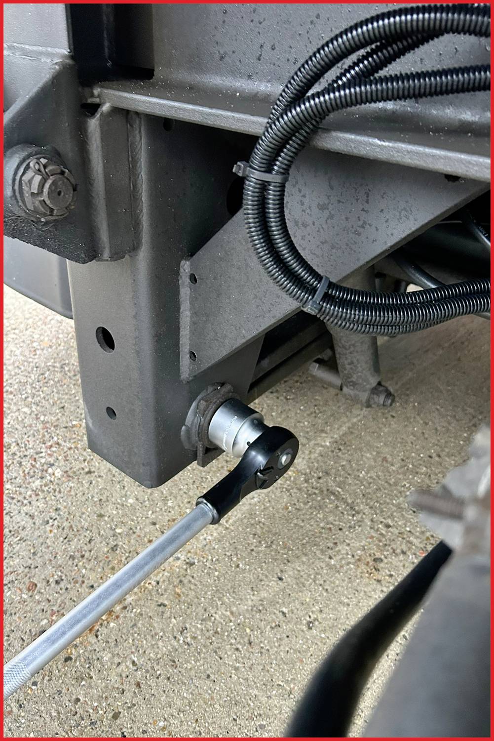 Eine Metallstange verbindet sich mit einem mechanischen Teil an einem Fahrzeug. Schwarze Kabel sind um das Fahrzeugteil gewickelt.
