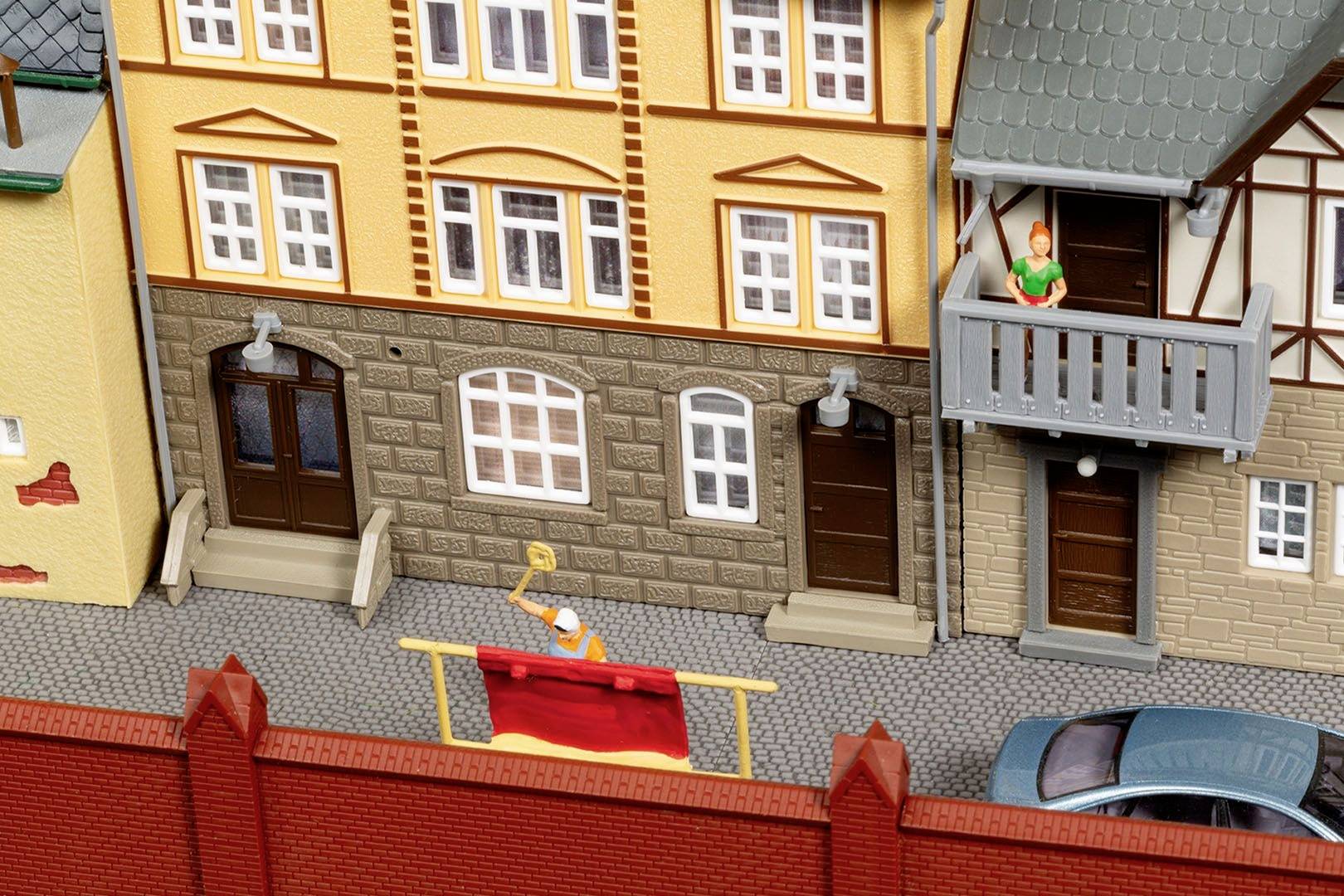 Ein Miniaturmodell einer Altstadtstraße mit Fachwerkhäusern. Eine winzige Figur wäscht ein rotes Tuch am Fenster.