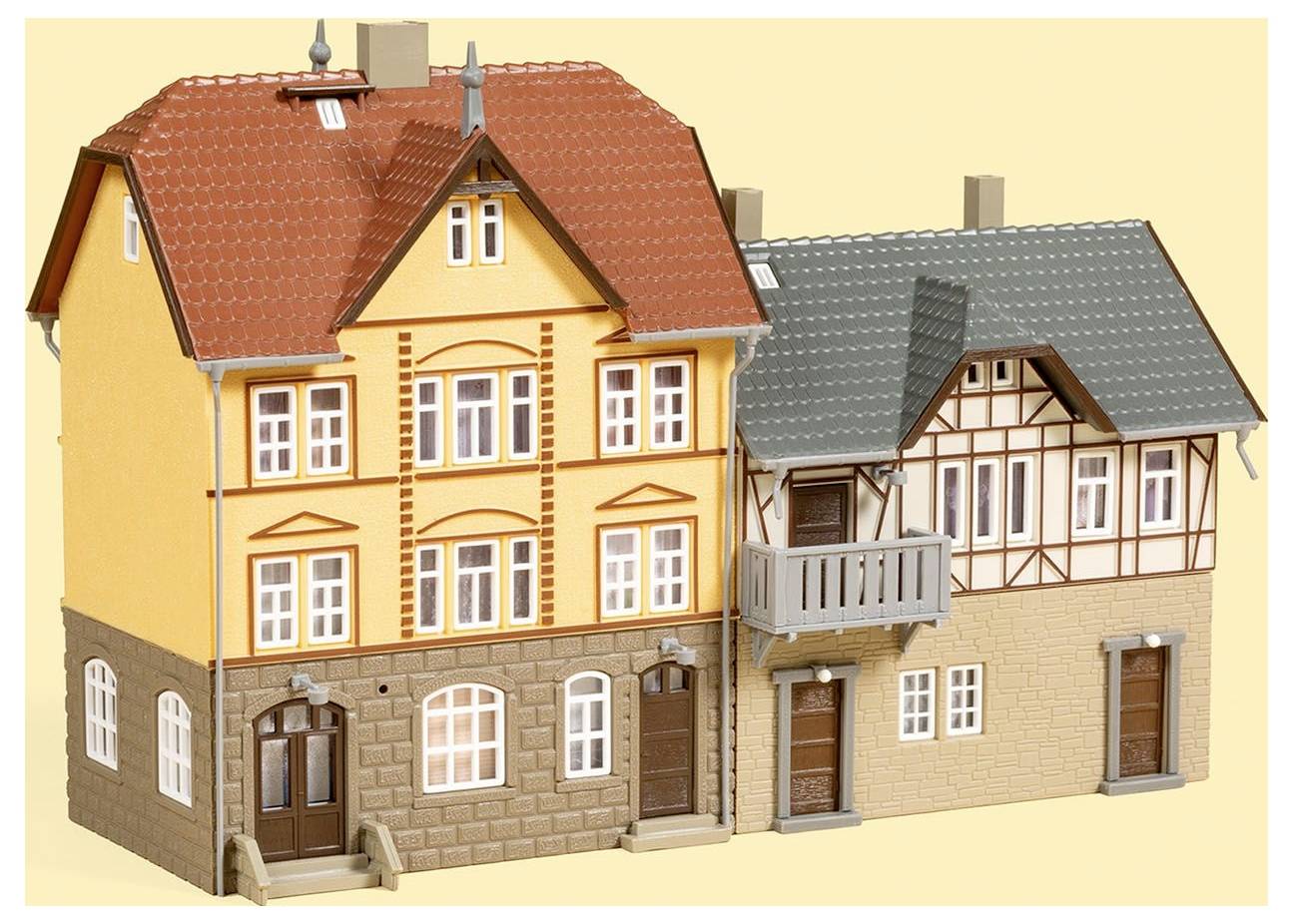 Zwei Modellhäuser im traditionellen deutschen Fachwerkstil, eines in Gelb mit rotem Dach und eines in Beige mit grauem Dach.