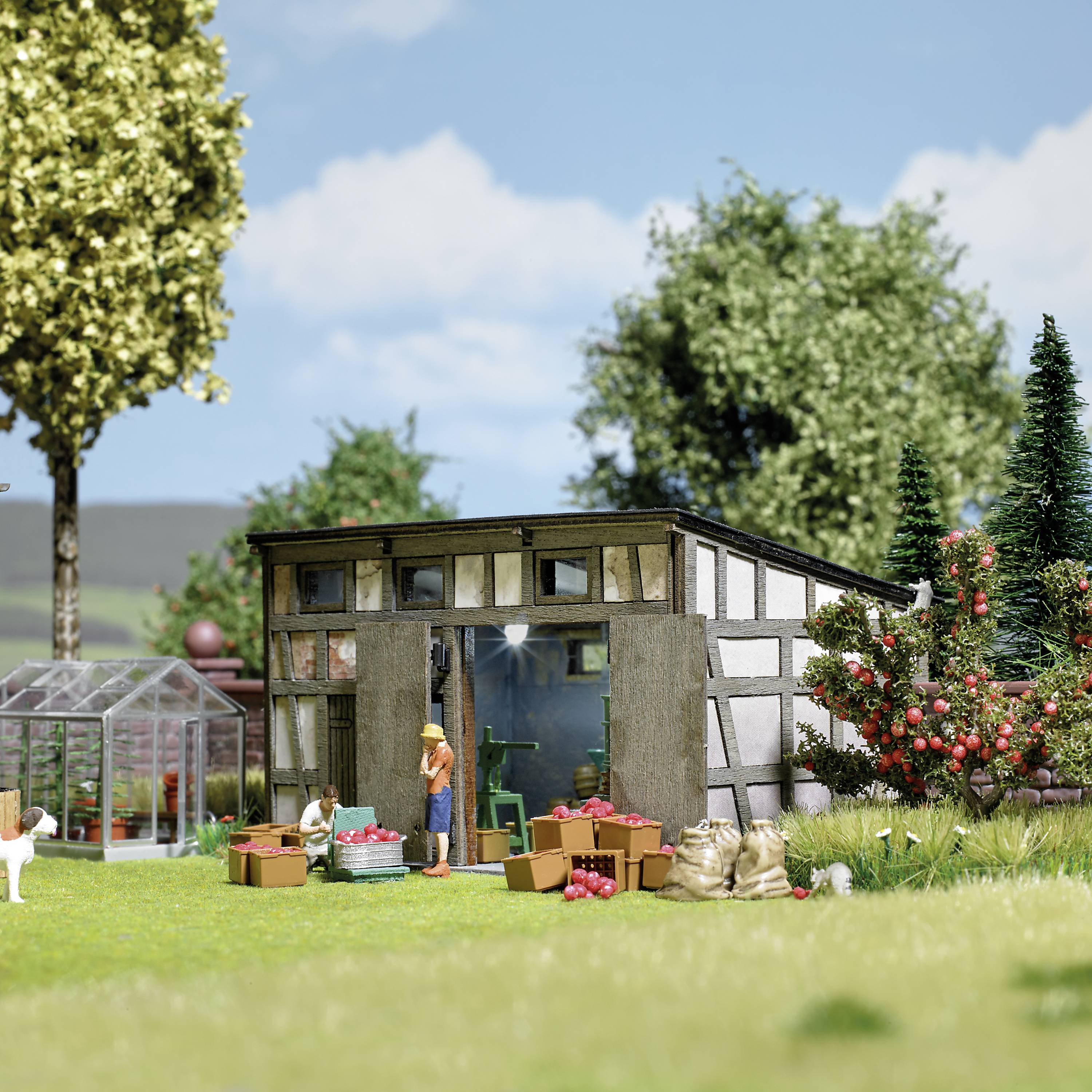 Eine ländliche Szene mit einer Scheune, Obst und Gemüse davor, ein Hund und ein Gewächshaus. Bäume im Hintergrund. Menschliche Aktivität sichtbar.
