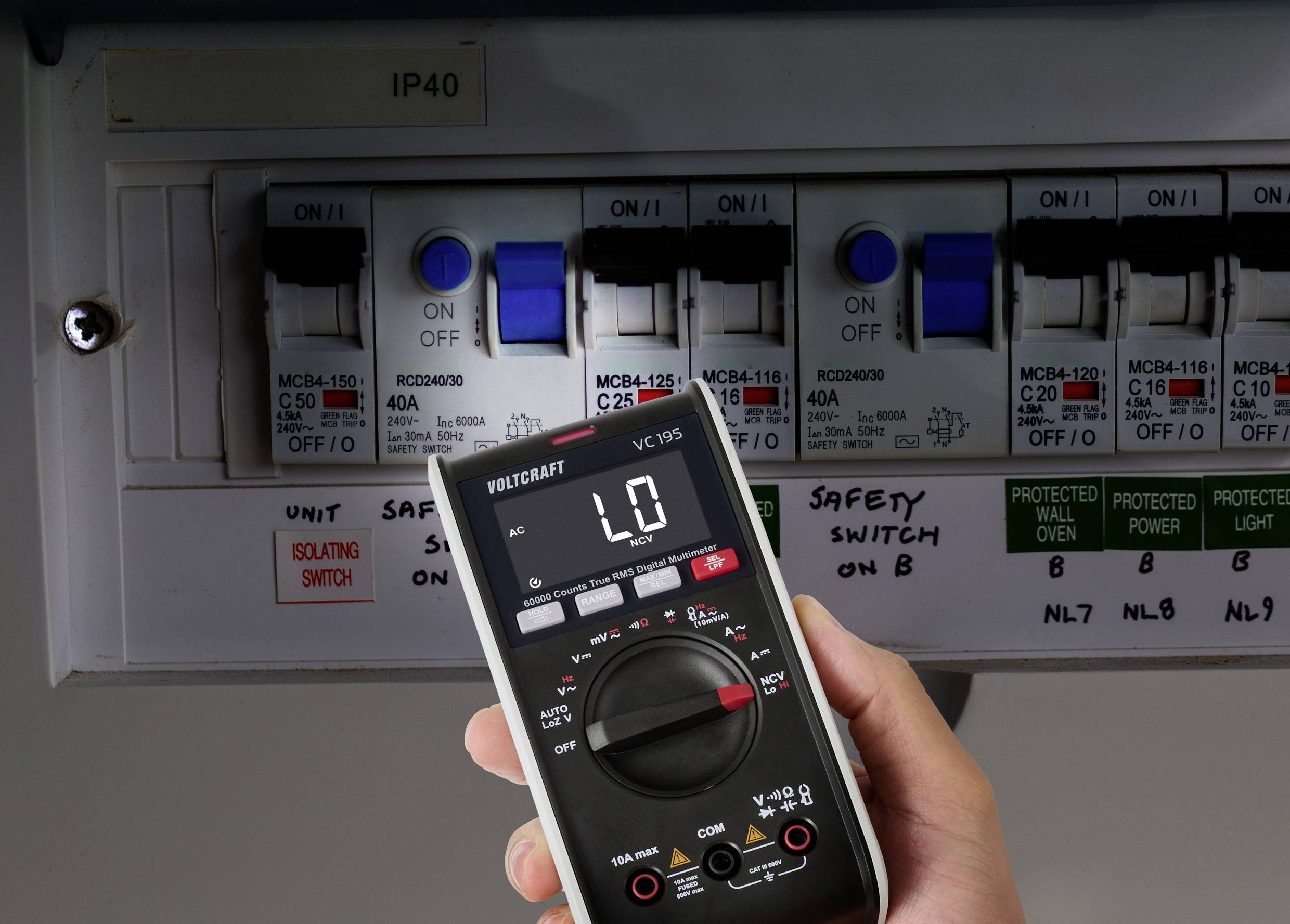 Eine Hand hält ein digitales Multimeter, das 'L0' nahe einer Elektrotafel mit mehreren Sicherungsautomaten zeigt, die mit 'MCB4-125' und 'RCBO40MLH' beschriftet sind.